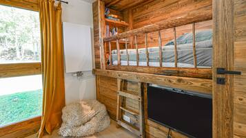 Uma cabana com beliche, um pequeno sofá, uma janela com cortinas e uma parede de madeira.