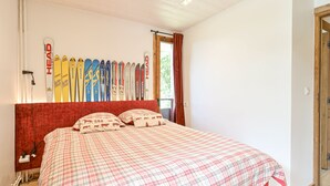 A bedroom with a bed, a headboard, and a row of skis on the wall.