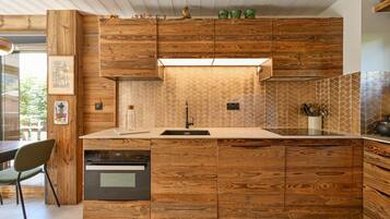 Cozinha moderna com armários de madeira, forno embutido e painel de azulejos em padrão herringbone.