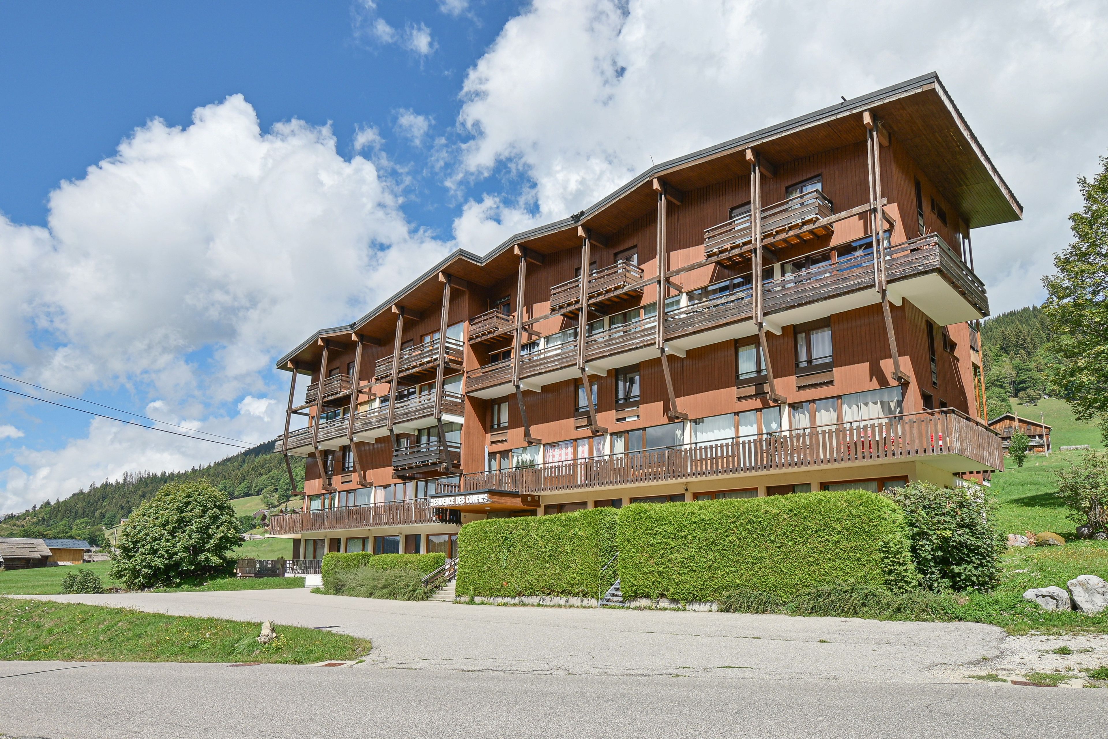 Un hôtel à plusieurs étages, doté de balcons, situé dans une région montagneuse sous un ciel dégagé.