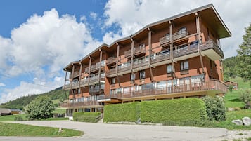 Un hôtel à plusieurs étages, doté de balcons, situé dans une région montagneuse sous un ciel dégagé.