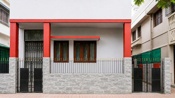 A building with a red and white facade, stone-textured walls, and a gated entrance. - Deluxe The Royal Orbit (Barasat)