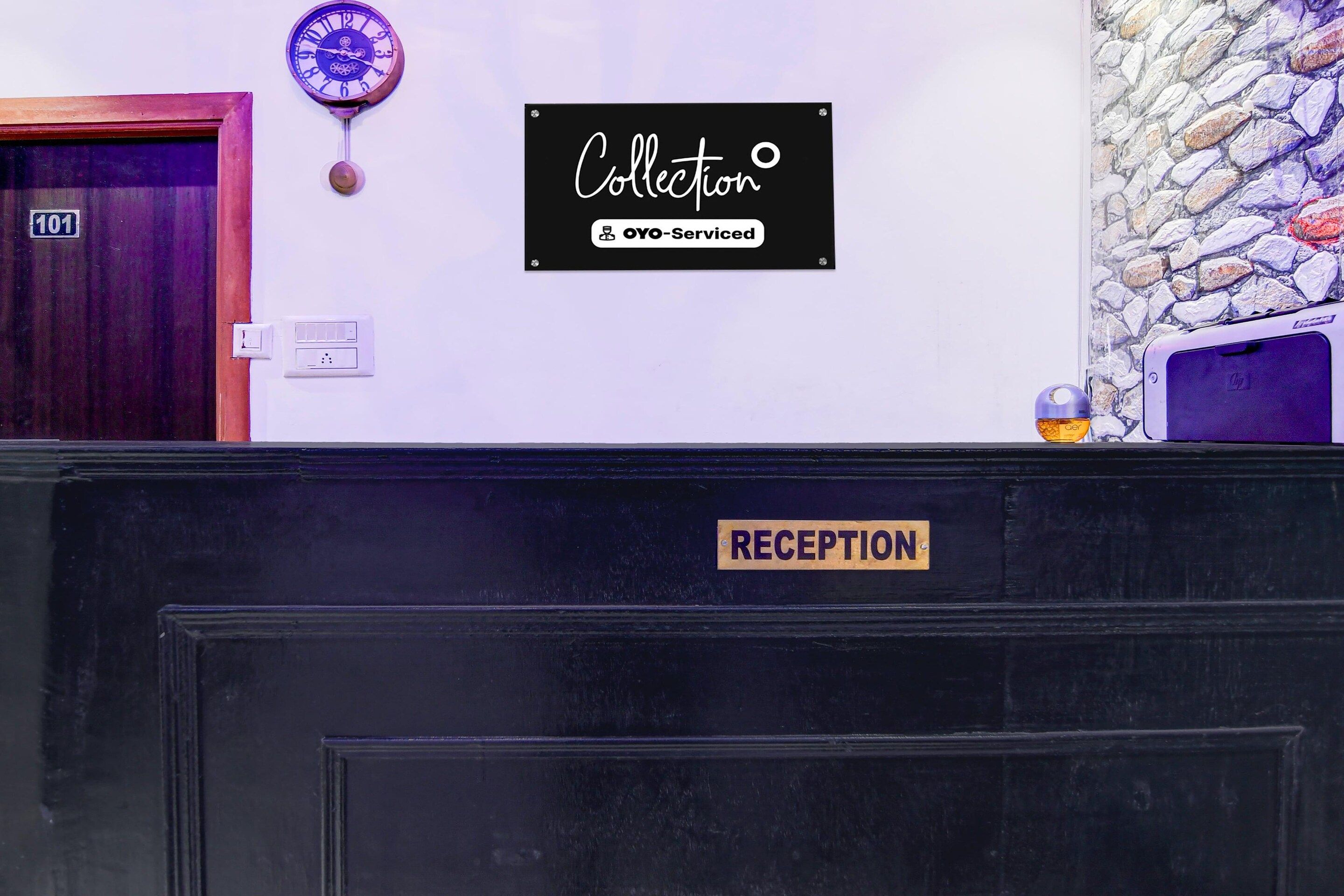 Ett receptionsområde med en skylt som visar ”RECEPTION” och en annan skylt ovanför som anger ”Collection OYO-Serviced”.