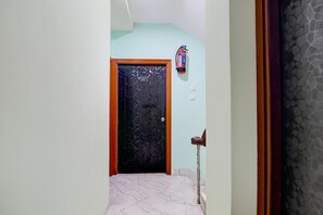 A hallway with a door marked '201', a fire extinguisher on the wall, and a handrail on the right. - Deluxe The Royal Orbit (Barasat)