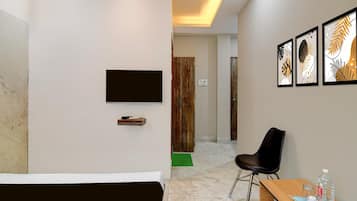 Una camera d'albergo con un letto, una scrivania con una sedia, una TV a schermo piatto e opere d'arte appese al muro.