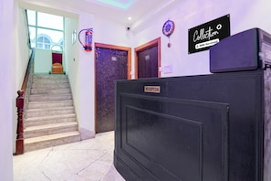 Ein Hotel-Empfangsbereich mit einer Rezeption, einer Uhr und einer Treppe zu einem Zimmer.