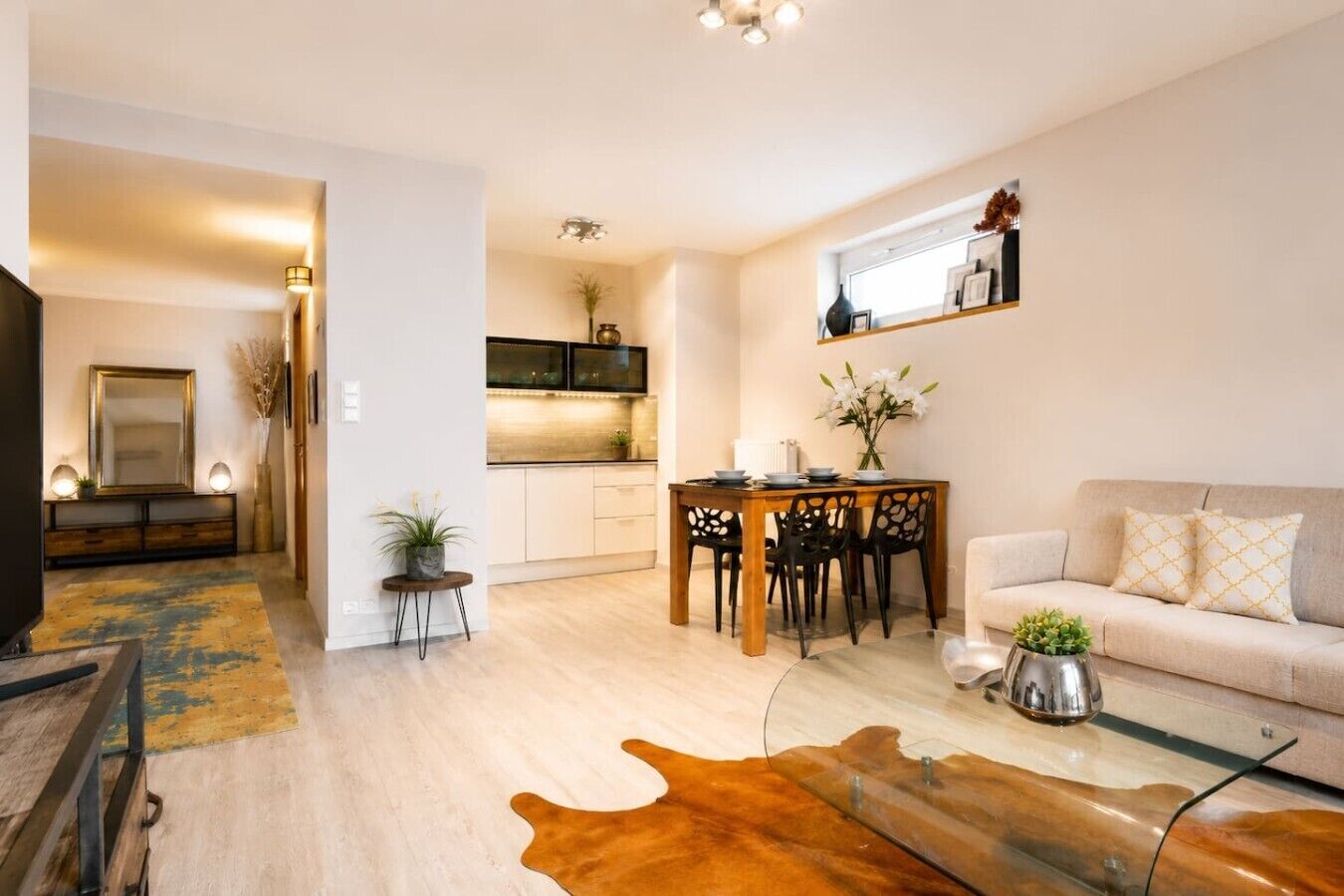 Un salon moderne comprenant un canapé, une table basse en verre et un coin repas avec une table et des chaises.