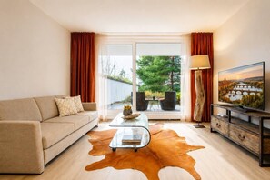 A modern living room with a sofa, coffee table, and TV. - Garden Oasis Apartment (Prague 2)