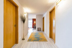 A hotel hallway with wooden doors, a floor lamp, and a rug. - Garden Oasis Apartment (Prague 2)