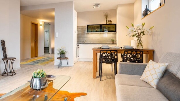 A modern living room with a sofa, a coffee table, and a dining area with chairs. - Garden Oasis Apartment (Prague 2)