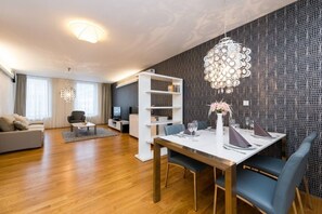 A modern living room with a dining area, wooden flooring, and a unique wall pattern. - Riverside Urban Oasis • AC • Stylish Karlín (Karlín)