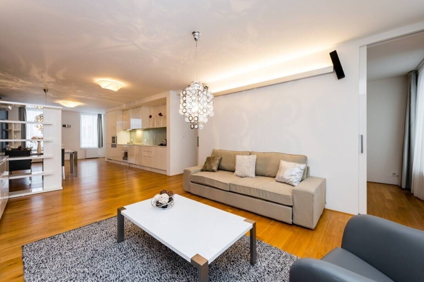 A modern living room with a sofa, a coffee table, and a chandelier.