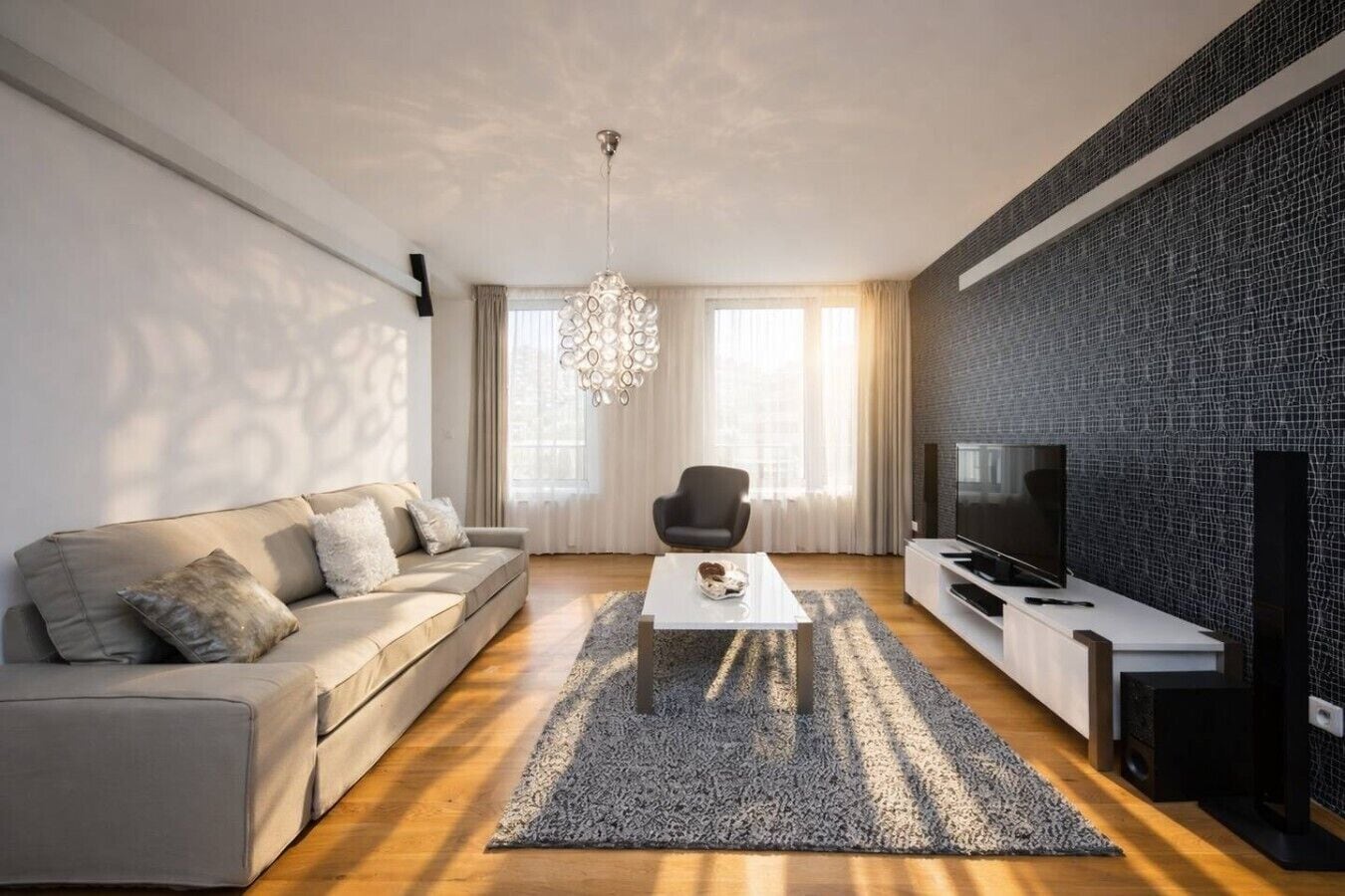 Ein modernes Wohnzimmer mit einer Couch, einem Couchtisch, einem Fernseher und einer Kronleuchter.