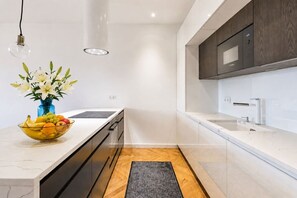 A modern kitchen with a marble countertop, a built-in oven, and a Bosch microwave. - Elegant City View Apartment with AC (Praha 3-Žižkov)