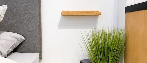 A minimalist bedroom with a bed, bedside table, and a wall-mounted shelf.