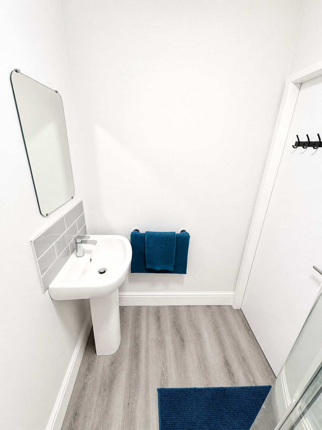 A bathroom with a white sink, a mirror, and a blue towel on a rack.