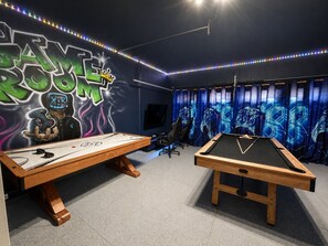 Ein Raum mit Billardtisch, Tischfußball und einer Wand mit Graffiti.