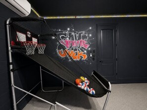 A basketball hoop with a net, a wall with graffiti art, and a door in a dark room. - Private Pool & Spa | Game Room | Sleeps 13 (Kissimmee)