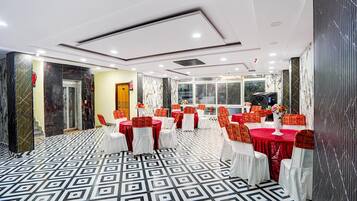 Une salle de banquet avec des tables rondes, des chaises blanches et un sol à motifs.