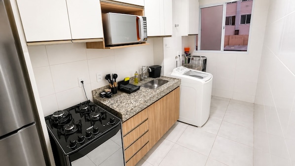 A compact kitchen with a gas stove, a microwave, and a built-in dishwasher.