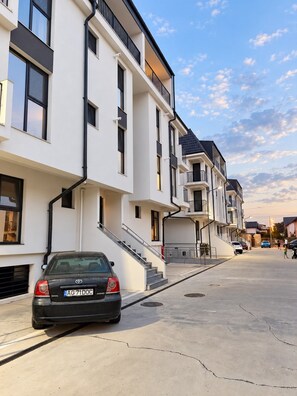 A modern residential building with a car parked in front. - Myonna Style AIRPORT 1 - Otopeni - Therme (Otopeni)