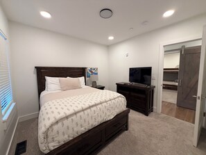 A bedroom with a bed, a TV, a desk, and a wardrobe. - 4-bedroom condo on Lone Peak mountain.  Not near the mountain. On it! (Big Sky)
