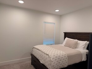 A bedroom with a bed, a nightstand, a window with blinds, and a ceiling light. - 4-bedroom condo on Lone Peak mountain.  Not near the mountain. On it! (Big Sky)