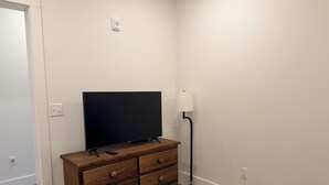 A room with a wooden dresser, a television, a lamp, and a carpeted floor. - 4-bedroom condo on Lone Peak mountain.  Not near the mountain. On it! (Big Sky)