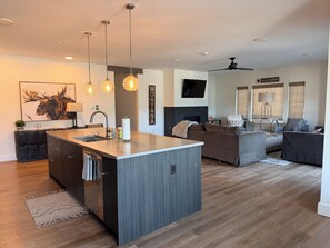A modern kitchen with a central island, a dining area with a sofa, and a living room with a television. - 4-bedroom condo on Lone Peak mountain.  Not near the mountain. On it! (Big Sky)