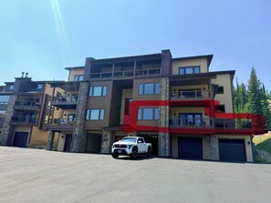 A multi-story residential building with a white pickup truck parked in the driveway. - 4-bedroom condo on Lone Peak mountain.  Not near the mountain. On it! (Big Sky)