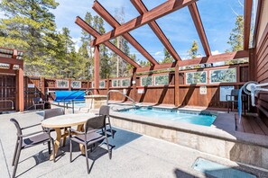 Eine Holzterrasse mit Pool, Sitzgelegenheiten im Freien und einem überdachten Bereich.
