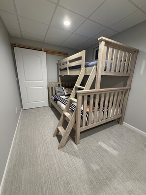 Ein Stockbett mit Holzlade, einer Tür und einer Deckenleuchte.