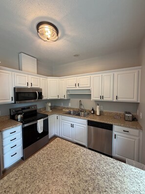 A kitchen with white cabinets, a stainless steel microwave, a stove, and a dishwasher. - Private Lakeview Retreat on 1+ Acre - Quiet, Scenic, Close to Everything (Augusta)