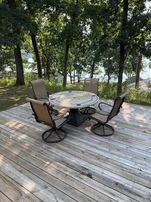 A round table with four chairs on a wooden deck, surrounded by trees and overlooking a body of water. - Private Lakeview Retreat on 1+ Acre - Quiet, Scenic, Close to Everything (Augusta)