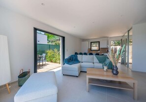 A modern living room with a sofa, a coffee table, and a dining area with chairs. - Villa contemporaine plein sud & piscine (Roquebrune-sur-Argens)