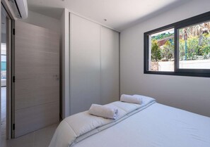 Un dormitorio con cama, armario y ventana con vistas a zonas verdes.