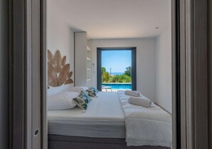Een slaapkamer met een bed, uitzicht op een zwembad en een balkon.