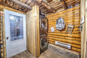 L’intérieur d’une cabane en bois, avec une porte, un lave-linge et un panneau indiquant la présence d’un service de blanchisserie.