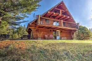 Une cabane en rondins dotée d’un balcon, d’une porte et d’un petit espace porche.