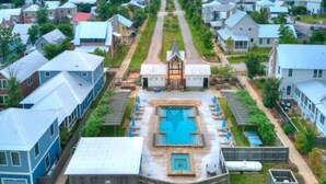 Quartiere residenziale con case, una strada centrale e una piscina.