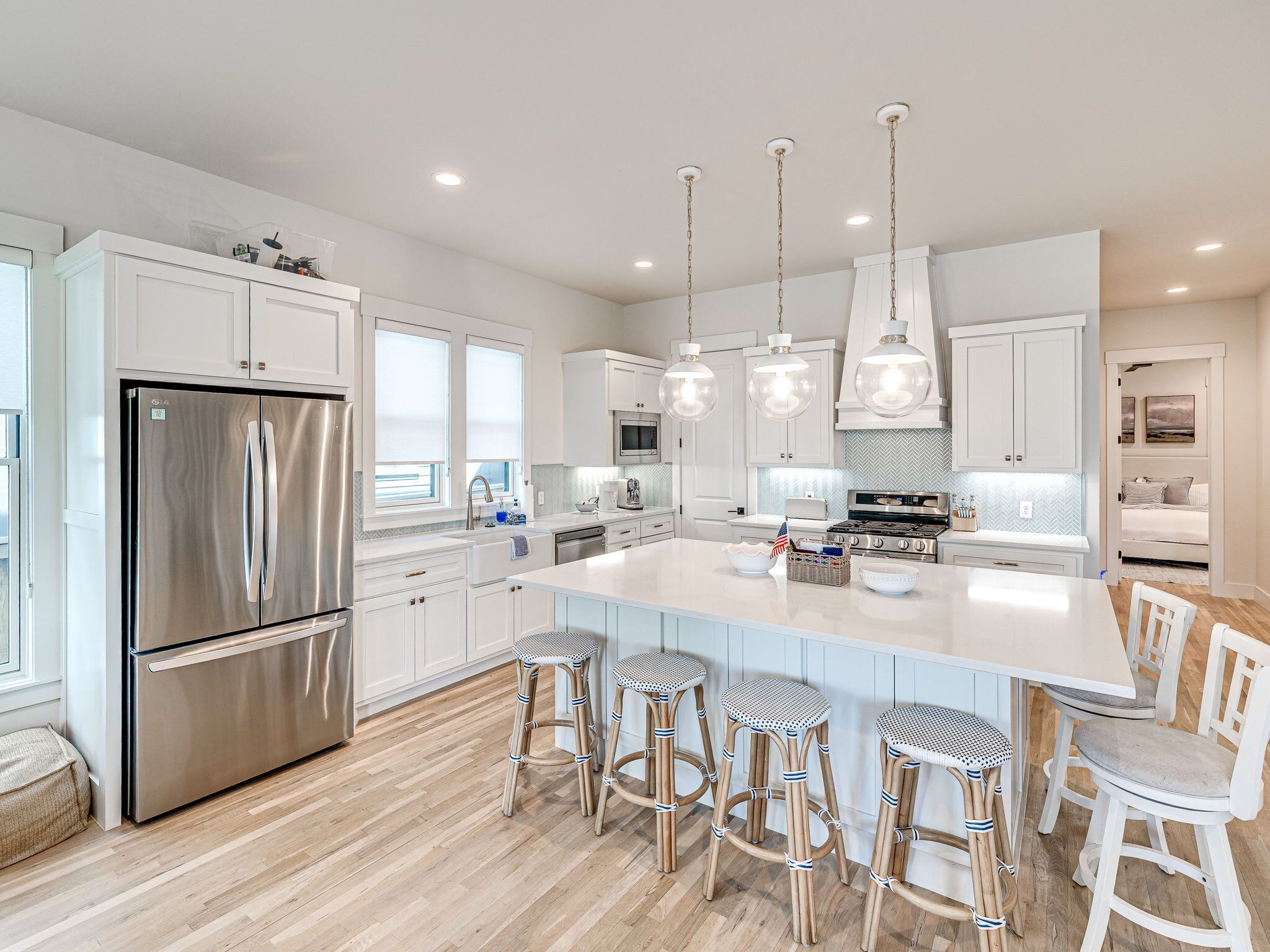 A modern kitchen with white cabinetry, stainless steel appliances, and a central island with bar stools.