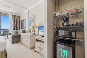 Ein Hotelzimmer mit Balkon, Schreibtisch mit Lampe, Kaffeemaschine, Mikrowelle und Fernseher.