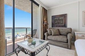 Ein Balkon mit Blick auf den Strand, eine Sitzecke, eine Lampe und ein gerahmtes Kunstwerk.