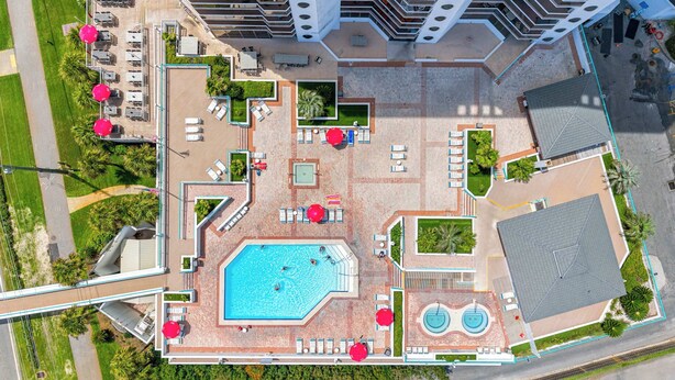 An aerial view of a hotel with a central swimming pool, multiple lounge areas, and a covered outdoor seating area. - Beach View Studio with Private Balcony, Pool, Hot Tub & Resort Access (Miramar Beach)