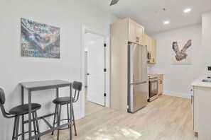 Una cocina moderna con refrigerador de acero inoxidable, armarios de madera y encimera blanca.