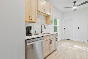 A kitchen with a dishwasher, a coffee maker, and a sink. - The Graffiti Loft - Artsy 1BR Near Downtown Pensacola (Pensacola)