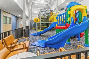 A children's play area with slides and climbing structures, carpeted flooring, and seating areas with chairs. - Ski IN/Ski OUT Snowshoe Rental (Snowshoe)
