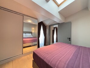 A bedroom with a bed, a wardrobe, and a skylight. - Top-floor 1BR with private terrace (Istanbul)