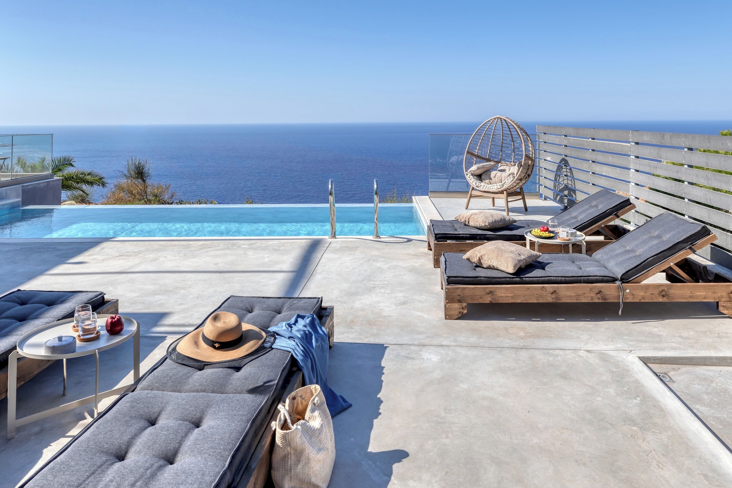Une terrasse sur le toit avec une piscine, des chaises longues, un fauteuil suspendu et une table où sont servis des boissons et des collations.