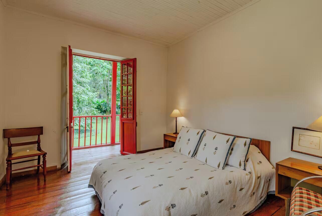A bedroom with a bed, a chair, a nightstand, and a door leading to a balcony.